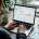 Small business HR manager reviewing candidate applications on a laptop with a recruitment dashboard, coffee mug and CVs on desk